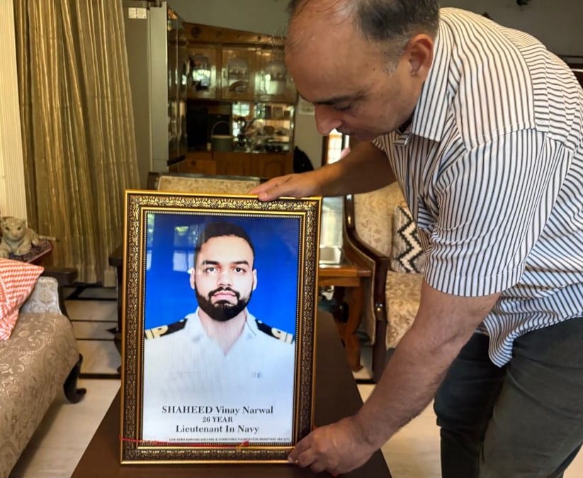 Rajesh Narwal holding a framed photo of son Vinal Narwal 