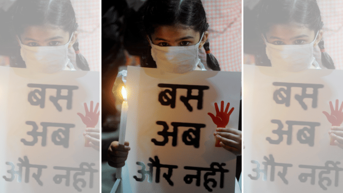 A child holds a candle and placard during a protest over crime against women | ANI File