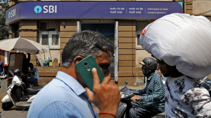 People move past a branch office of State Bank of India (SBI) in Mumbai. | Niharika Kulkarni/Reuters