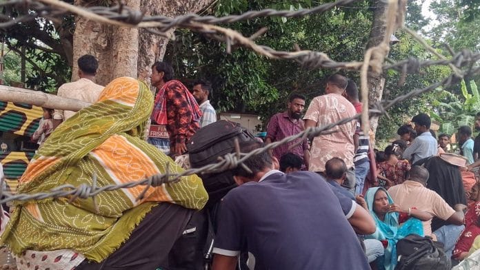 Several men, women, and children waiting with luggage beside the BSF checkpost at the Hakimpur outpost near Bangladesh border in North 24 Parganas, West Bengal Wednesday | ANI