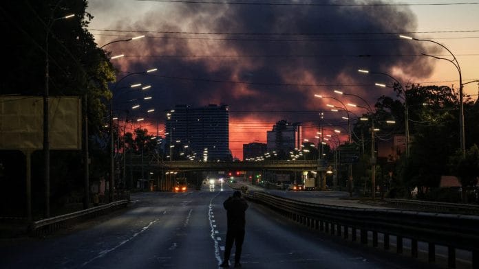 A man takes a picture of a street as smoke rises in the background after an overnight Russian missile and drone strike, amid Russia's attack on Ukraine, in Kyiv, Ukraine June 2, 2026. | REUTERS/Alina Smutko