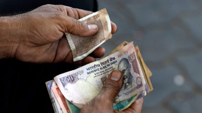 FILE PHOTO: A cashier holds Indian currency notes at a fuel station in Ahmedabad, India, May 20, 2026. REUTERS/Amit Dave/File Photo