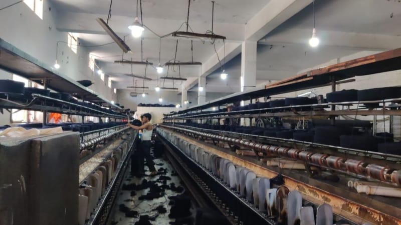 एक कर्मचारी बिना किसी सुरक्षा उपकरण के कटी हुई फाइबर को धागा बनाने वाली मशीन में डालता हुआ | फोटो: वितस्ता कौल/दिप्रिंट