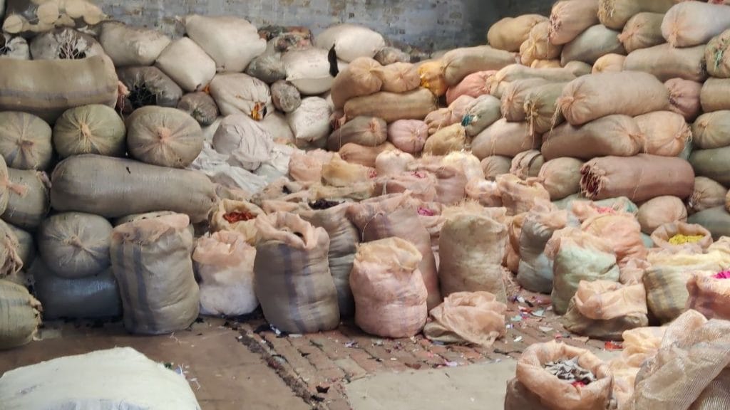 Women workers rest on heaps of textile waste inside a recycling unit. Vitasta Kaul | ThePrint