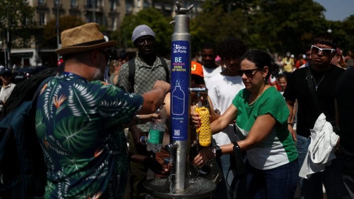 People refill water bottles from a public fountain near the Place du Trocadero during high temperatures amid a heatwave in Paris, France | REUTERS