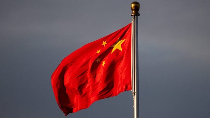 China’s national flag flutters in the wind lit by sunrise in Beijing, China, November 20, 2025. | REUTERS/Maxim Shemetov