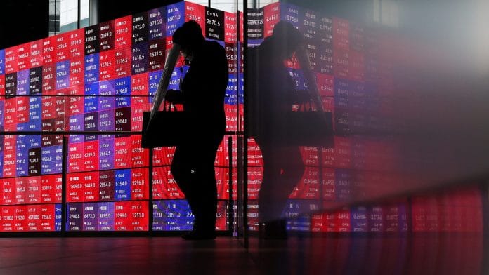 A man walks in front of an electronic screen displaying Japan's Nikkei stock prices quotation board inside a conference hall in Tokyo, Japan, April 27, 2026. | REUTERS/Issei Kato/File Photo