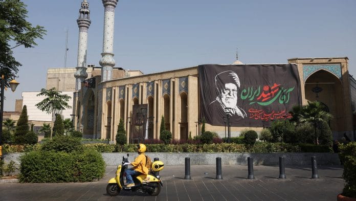 An Iranian woman rides a motorcycle next to a banner with a picture of the late Supreme Leader of Iran, Ayatollah Ali Khamenei, on a street in Tehran, Iran Majid Asgaripour WANA (West Asia News Agency) via REUTERS