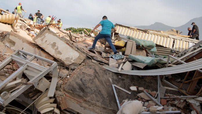 A volunteer walks on debris from a collapsed building following twin earthquakes in Caraballeda, La Guaira State, Venezuela, on June 25. Photographer: Donaldo Barros/AFP/Getty Images