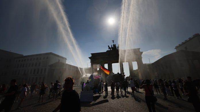 Police spray water canon at the Brandenburg Gate during a heat wave in Berlin in June. | Bloomberg