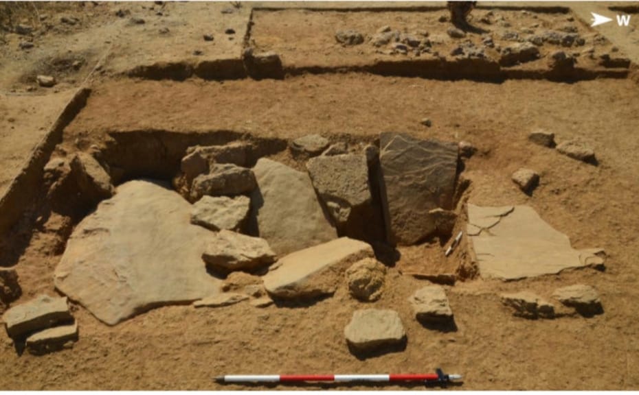 A pot burial with capstones exposed during excavations at Dhaneti, Gujarat. Remains of a stone circle surrounding the burial pit are visible in the background | Photo by special arrangement