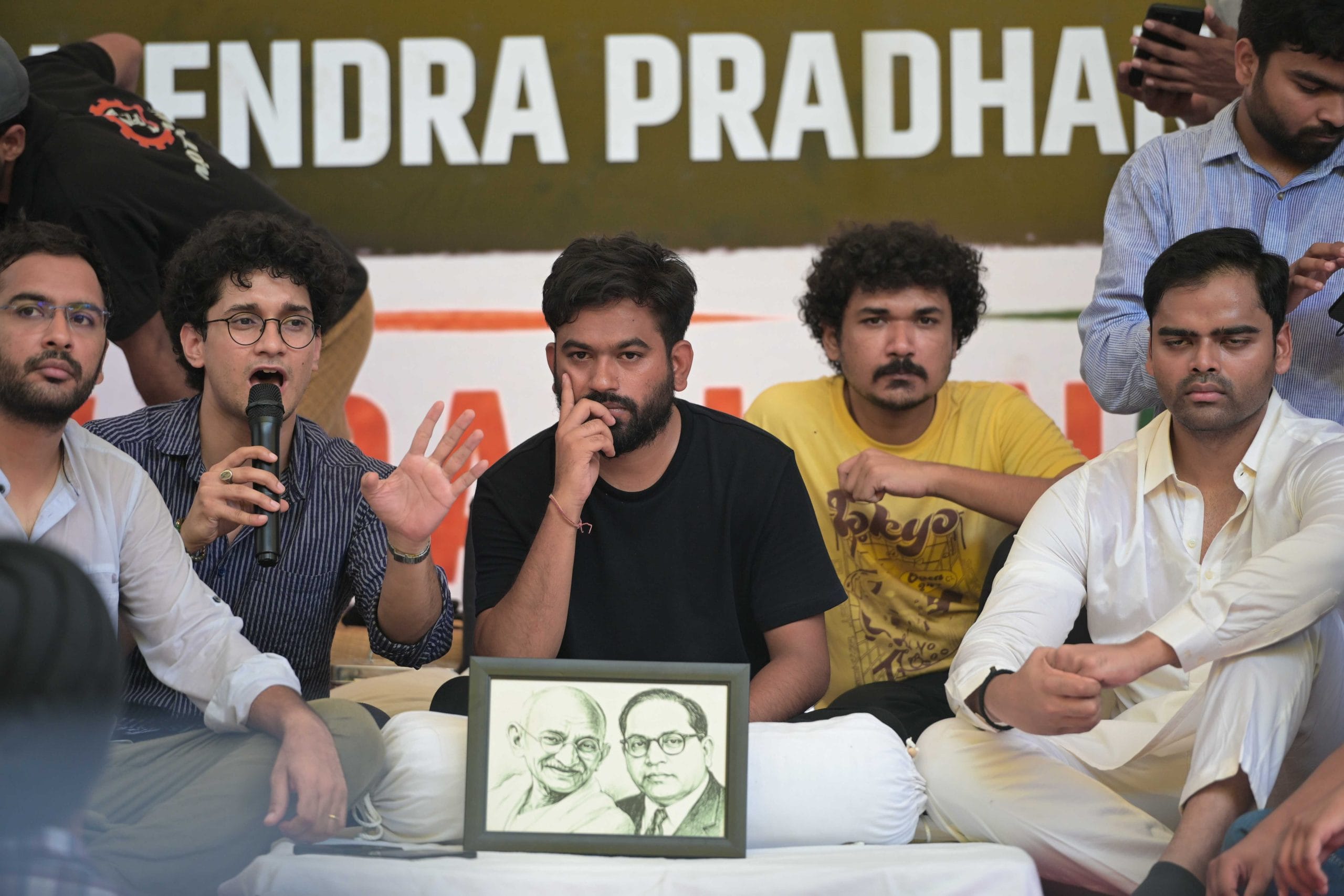 Cockroach Janta Party leader Abhijit Dipke sitting with a photograph of Wanghchuk at Jantar Mantar protest site | Suraj Singh Bisht | ThePrint