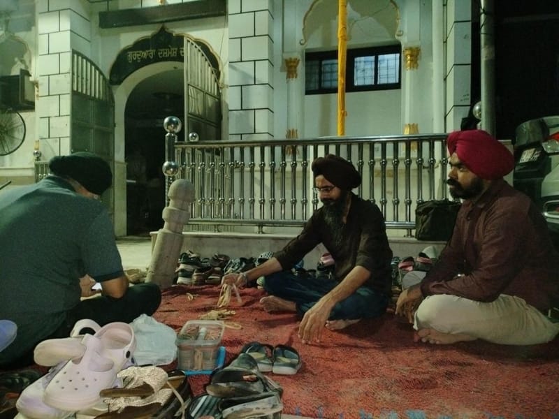 प्रवेश द्वार पर सुखबीर और दूसरे स्वयंसेवक लोगों के जूते संभाल रहे थे | फोटो: हर्ष तिवारी/दिप्रिंट