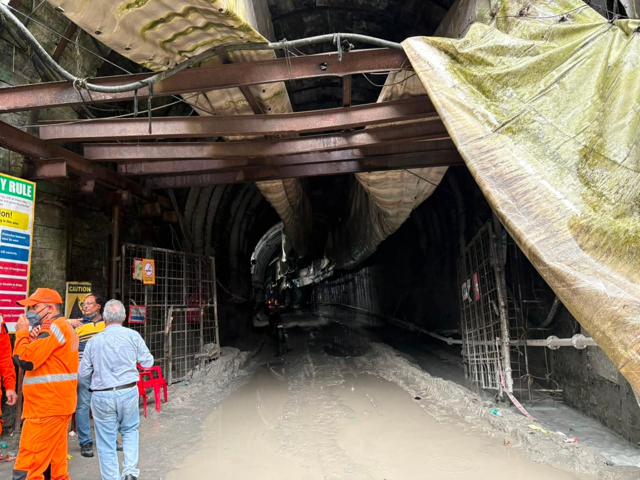 Rescue and NDRF personnel at the mouth of the tunnel, with warning and safety-rule signage visible alongside the debris-strewn passage beyond | Photo: Sakshi Mehra/ThePrint