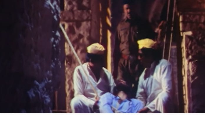 A still from 'Maachis', with two men holding an unconscious man, with the figure of a policeman at the back