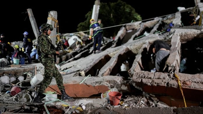 A member of the military walks as rescuers work amidst the debris at the Torres de Limonar building in the aftermath of an earthquake, in Cali, Colombia, August 11, 2026. | Sergio Acero / REUTERS