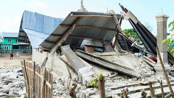 A person walks near a heavily-damaged house after an earthquake felt in Nanga Mbaur village, East Manggarai, East Nusa Tenggara province, Indonesia, August 16, 2026. | Gabrin Anggur / REUTERS