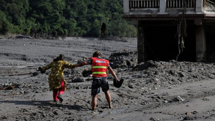 A rescuer helps a woman to move through a muddy road following flash floods and a mudslide in Trishuli, Nuwakot district, Nepal, August 28, 2026. | REUTERS/Navesh Chitrakar TPX IMAGES OF THE DAY
