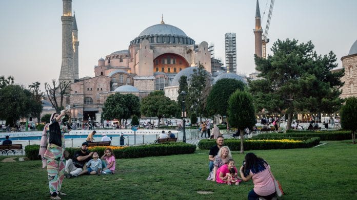 Tourists take pictures in front of the Hagia Sophia Grand Mosque in Istanbul. Photographer: Chris McGrath/Bloomberg