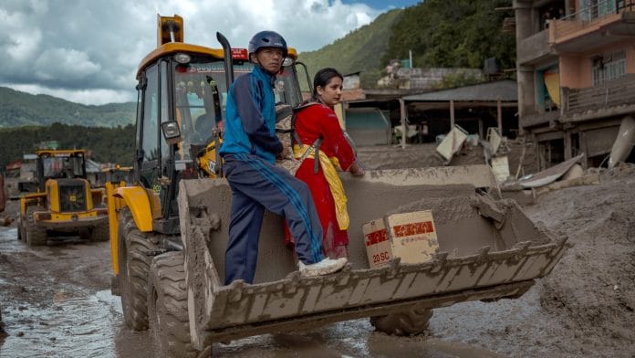 A resident receives assistance to get across heavy mud in Trishuli, Nepal, on Aug. 27. Photographer: Ezra Acayan.