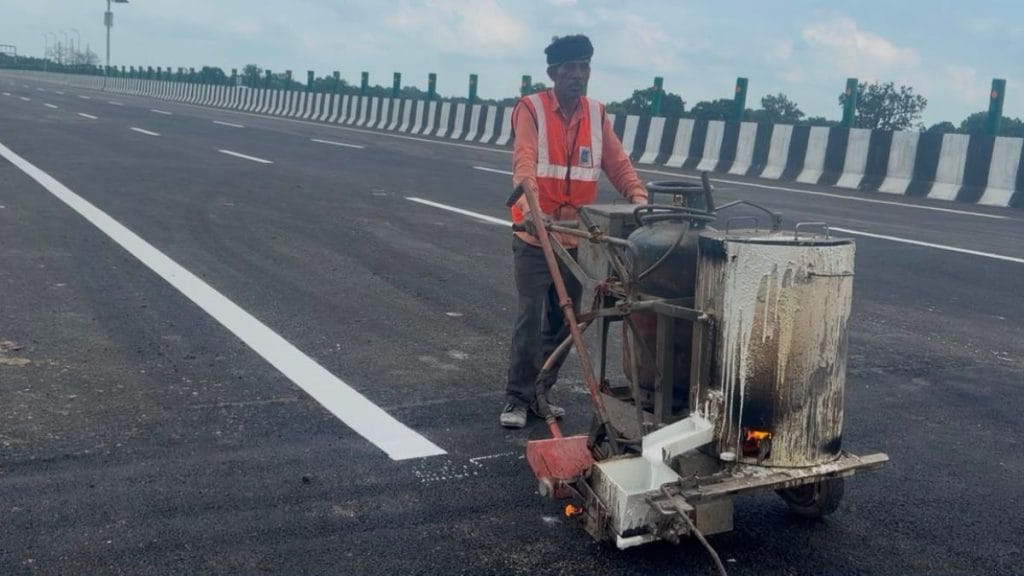 At the 64 km mark towards Lucknow, where the biggest cave-in was reported, a worker lays a fresh road line at the repatched stretch. Saman Husain | ThePrint