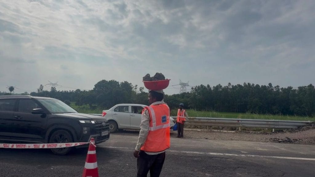 A worker waits for high-speed traffic to pass before dumping construction debris he has manually pulled from the road onto the other side of the expressway. Saman Husain | ThePrint
