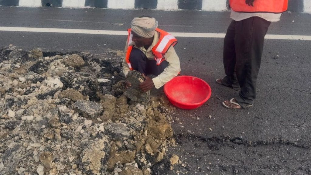 A worker manually clears a damaged section of the expressway, removing broken chunks of asphalt and debris with his hands. Saman Husain | ThePrint