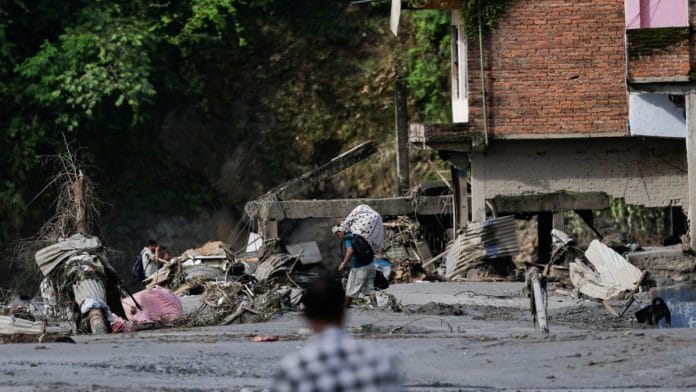 A man carrying his belongings moves through debris following devastating floods, in Trishuli in Nuwakot district, Nepal, on 27 August, 2026 | Navesh Chitrakar/Reuters
