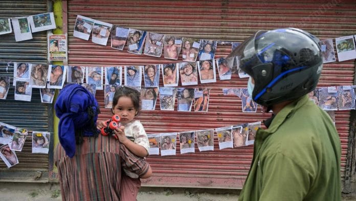 Family members and relatives trying to identify their loved ones from the pictures of bodies recovered from the flood outside a morgue. | Suraj Singh Bisht/ThePrint