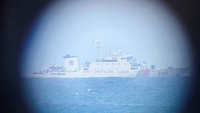 A China Coast Guard ship on the horizon through a telescopic view in Philippine-occupied Thitu Island in the disputed South China Sea, February 21, 2026. Picture taken with a mobile phone. REUTERS/Karen Lema
