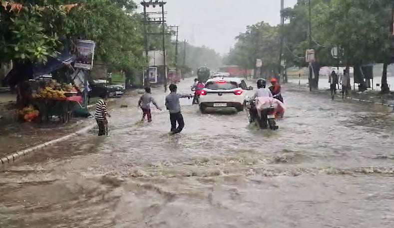 Commuters wade through a waterlogged road, in Gurugram on 7 August, 2026 | ANI