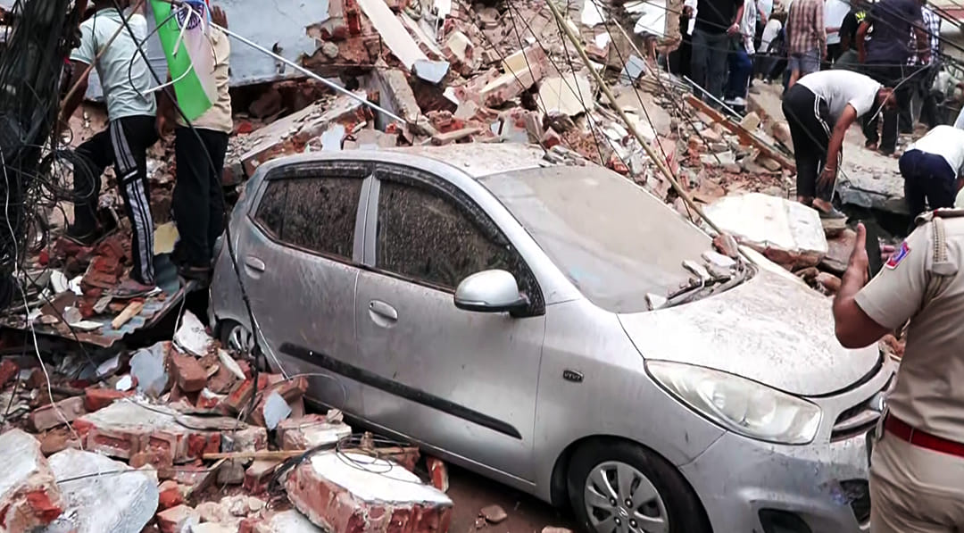 A damaged car under debris after the building collapse in Satya Niketan | ANI Video Grab