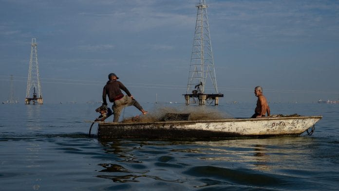 Fishermen drive past Petroleos de Venezuela SA (PDVSA) oil rigs on Lake Maracaibo in Cabimas, Zulia state, Venezuela. | Gaby Oraa/Bloomberg