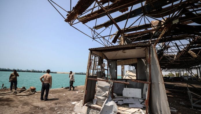Men gather at the damage to the storage and warehousing facilities at the port of Kuhestak following a US military strike earlier in the week on Kuhestak, Hormozgan province, Iran. | Bloomberg
