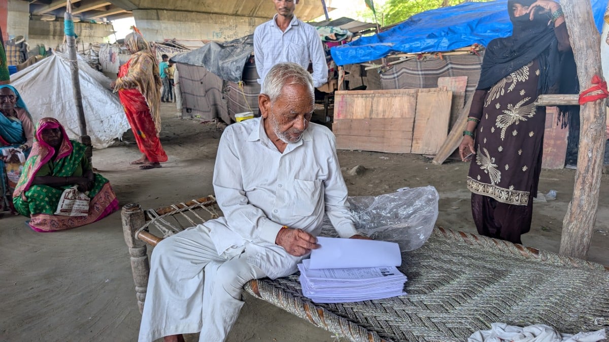 Ram Charan, 84, clutching photocopies of enumeration forms submitted by residents of Bela Estate | Apoorva Mandhani/ThePrint