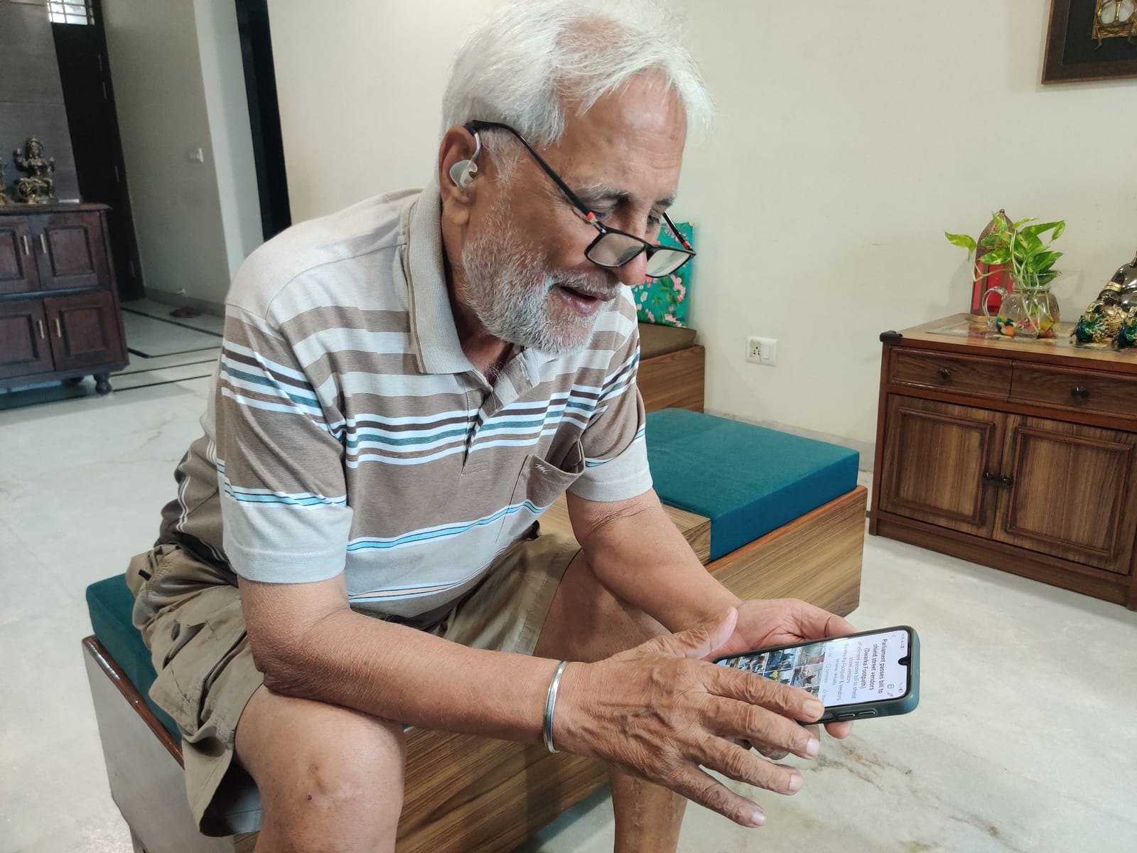 एस.के. मलिक अपने फोन पर द्वारका की तस्वीरें दिखाते हुए | फोटो: अलमिना खातून/दिप्रिंट