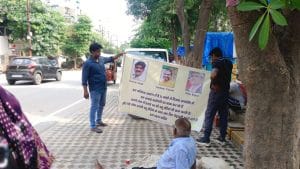 सफाई कर्मचारी न्याय की गुहार लगाते हुए एक बैनर लेकर आरडब्ल्यूए सदस्यों के नाम और तस्वीरें प्रदर्शित कर रहे हैं | फोटो: अलमिना खातून/दिप्रिंट
