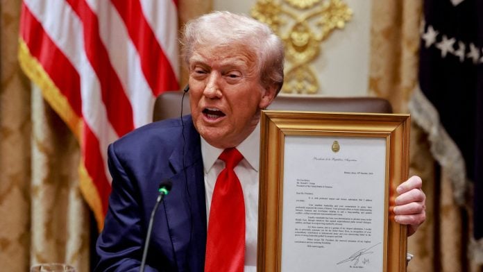 FILE PHOTO: U.S. President Donald Trump holds a framed letter from Argentina’s President Javier Milei stating that Milei nominates Trump for the Nobel Peace Prize, during lunch with Milei in the Cabinet Room at the White House in Washington, D.C., U.S., October 14, 2025. REUTERS/Jonathan Ernst/File Photo