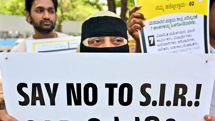 An anti-SIR protester holds a placard during a protest related to SIR issues, in Bengaluru on Saturday. | ANI