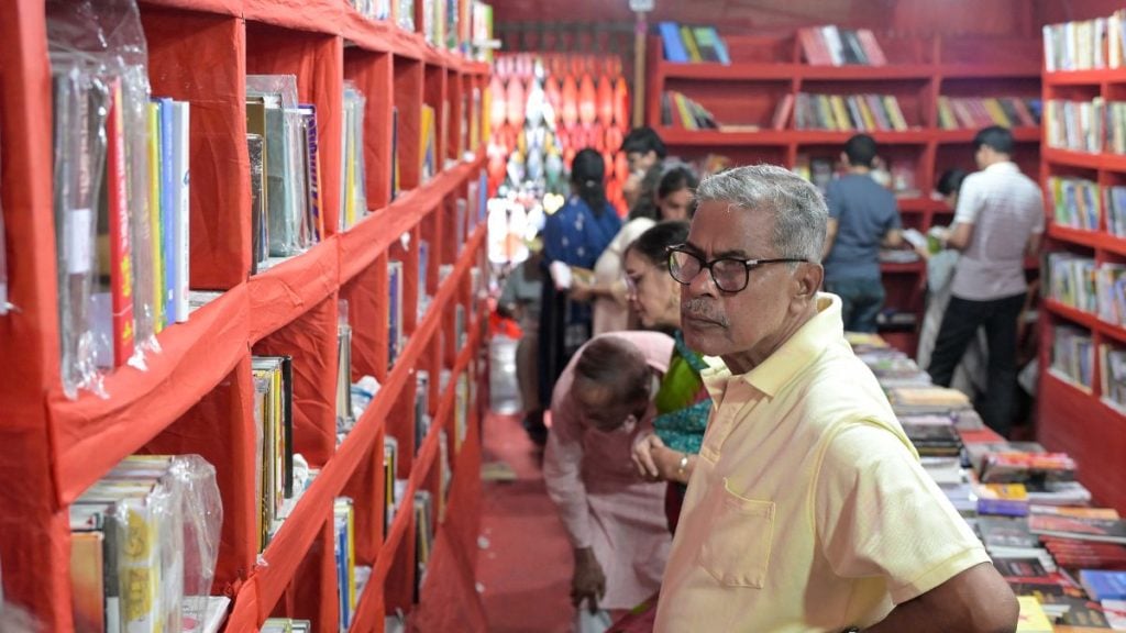 A pandal hopper peruses books at a Left bookstall in Kolkata. Suraj Singh Bisht | ThePrint