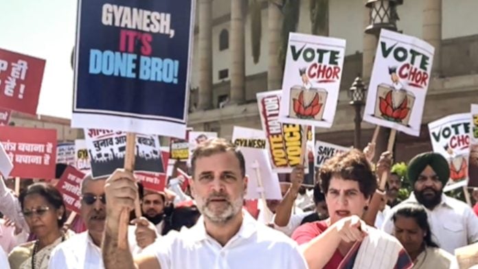 In this screengrab from a video posted on Oct. 6, 2026, Leader of Opposition in the Lok Sabha Rahul Gandhi holds a placard reading 'Gyanesh, It's Done Bro!' alongside Congress leader Priyanka Gandhi Vadra during an INDIA bloc protest march from Parliament toward the Election Commission office, demanding the resignation of Chief Election Commissioner Gyanesh Kumar, in New Delhi. (@RahulGandhi/X via PTI Photo)