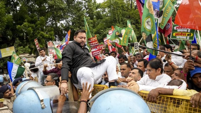 Patna: Bihar Leader of Opposition and RJD leader Tejashwi Yadav climbs over police barricades as police personnel attempt to stop him during the INDIA bloc's march to Lok Bhavan, in Patna, Thursday, Oct. 8, 2026. Opposition leaders and workers from RJD, Congress, and Left parties staged the demonstration against alleged irregularities in the Special Intensive Revision (SIR) of electoral rolls. (PTI Photo)