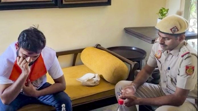 A Delhi Police official with Cockroach Janta Party (CJP) founder Abhijeet Dipke, ahead of the party's 'Lehra Do Tiranga' rally, at Dipke's residence in New Delhi, Friday, Oct. 16, 2026. | PTI Photo