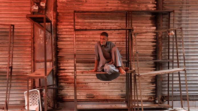 A salesman sits on iron frames outside closed shop in Pakistan (File Photo/ Reuters)