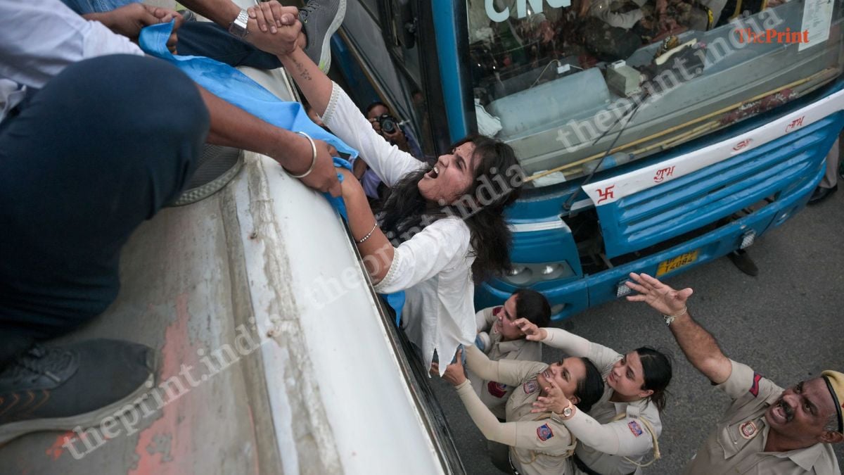 A protester grimaces as others try to haul her up to the roof of a bus | Suraj Singh Bisht | ThePrint