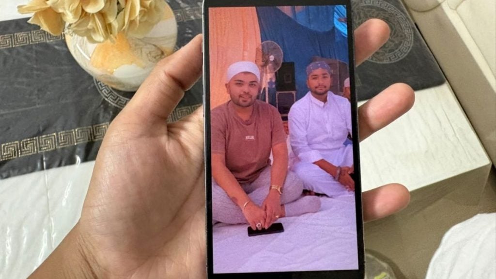 Madhusudan Sandhu with his 23-year-old brother. Their father show a photo of them on his phone. Sakshi Mehra | ThePrint